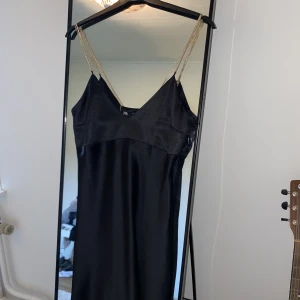 Zara sidenklänning (helt oanvänd) - Sidenliknande klänning köpt från Zara i april, aldrig använd! Snygg kedjedetalj i guldfärg. Väldigt smickrande och inte för kort i bak 🖤