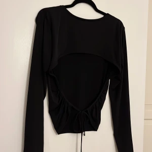 Topp med öppen rygg  - Snygg svart topp med öppen rygg, från Nelly storlek L
