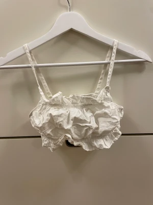 Litet vitt linne - Liten vit topp från hm med fina volanger längs under och översidan. Jättebra skick, knappt använd!