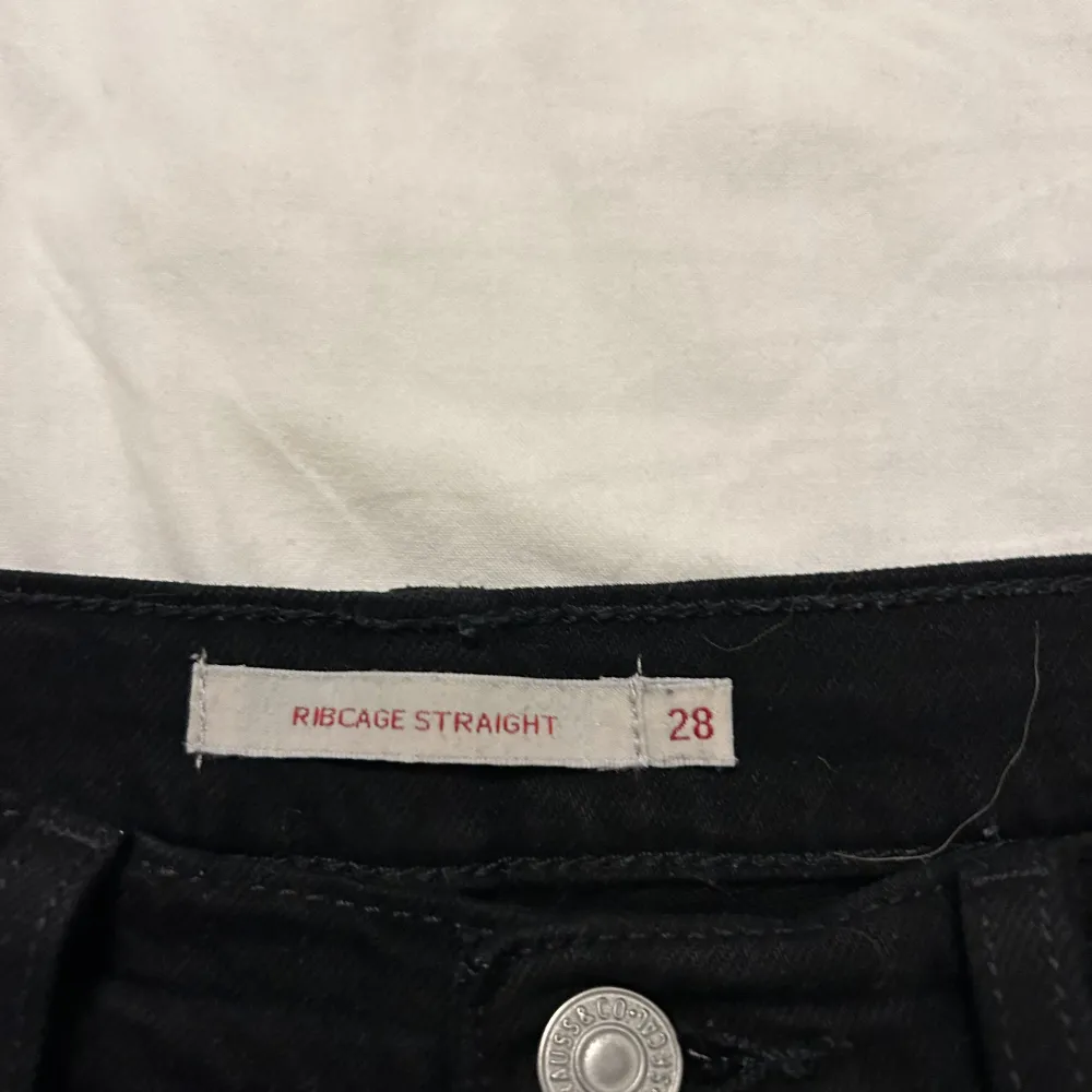 Ett par svarta levi’s Jeans i modellen ribcage  Tvättade en gång  Strl 28 De har en tightare passform upptill med straight passform i benen och lite vidare  Nypris: 1300  . Jeans & Byxor.