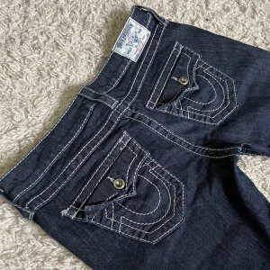 True Religion jeans - Bootcut och lågmidjad modell, har snygga detaljer bak och fram med vita stygn. ❤️ Innerben: 82cm, midja rakt över: 43cm. De är för stora för mig, kan fixa fler måt. 🫶 Håll koll på min profil, lägger för det mesta upp vintage jeans. 😍