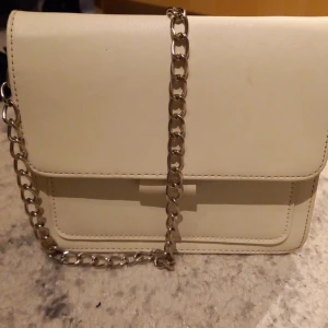 Väska - En vit väska med silver kedja. Super fin. Väl använd men super fin.