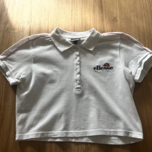 Kort t-shirt från Ellesse - Croppad t-shirt från Ellesse med rosa linjer uppe vid axlarna💗 Endast använd några få gånger, köpt på JD 