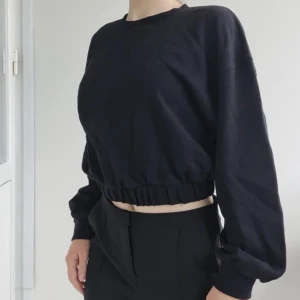 Svart tröja - Svart crewneck sweatshirt med resår i nederkanten, croppad längd, storlek S men passar nog även XS, fint skick, knappt använd. 