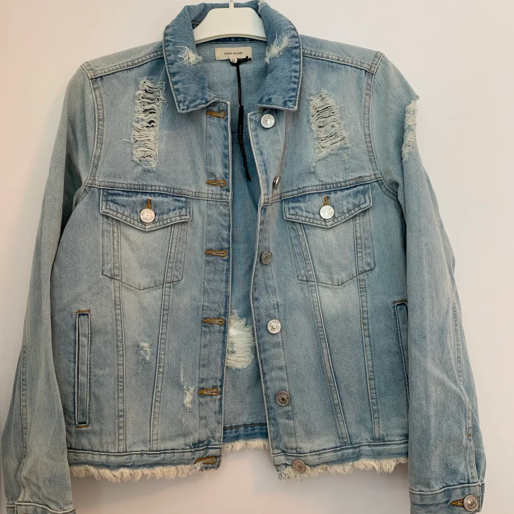 Helt ny, oanvänd, jeansjacka med prislappen kvar, från River Island i storlek 40. Jackan har en fin ljusblå färg och slitningar. Nypris ca 500kr.. Jackor.