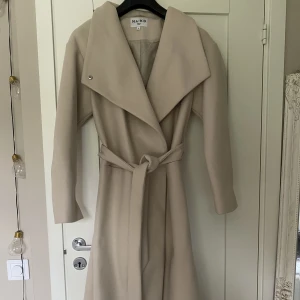 Beige kappa nakd  - Beige lång kappa från NAKD med knytning i midjan. Så himla fin men har tyvärr bara kommit till användning ett fåtal gånger för mig🤍köpt för 1500kr.