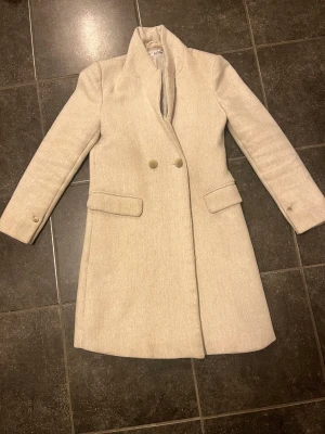 Kappa  - Snygg, stilren beige knälång kappa. Fint skick. 