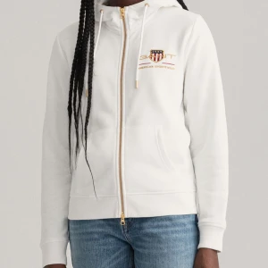 Archive Shield full-zip hoodie Gant  - Gant huvtröja i vit med guldiga detaljer😍 Storlek M, men passar xs/s om man vill ha lite ovesize  Som ny! Nypris: 1400kr  Passa på att köpa nu när det är fri frakt!😍