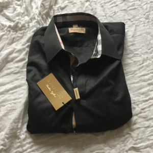 Svart Burberry Skjorta  - Helt oandvänd burberry skjorta. Tag finns på såklart. Säljer då jag köpte fel storlek till min kille. Storlek L. Pris kan diskuteras vid snabbaffär! Kom privat vid frågor och funderingar. 🫶🏼