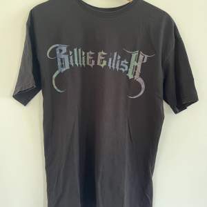 En oversized Billie Eilish t-shirt med tryck köpt från Bershka. I fint skick förrutom att pricken över det tredje ”i”et har åkt av. Texten på tröjan kan lysa i mörkret som ni ser på andra bilden. Storlek XS men känns mer som S-M