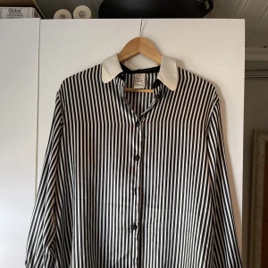 Skjorta - En vit-svart randig skjorta. Storlek: 42.