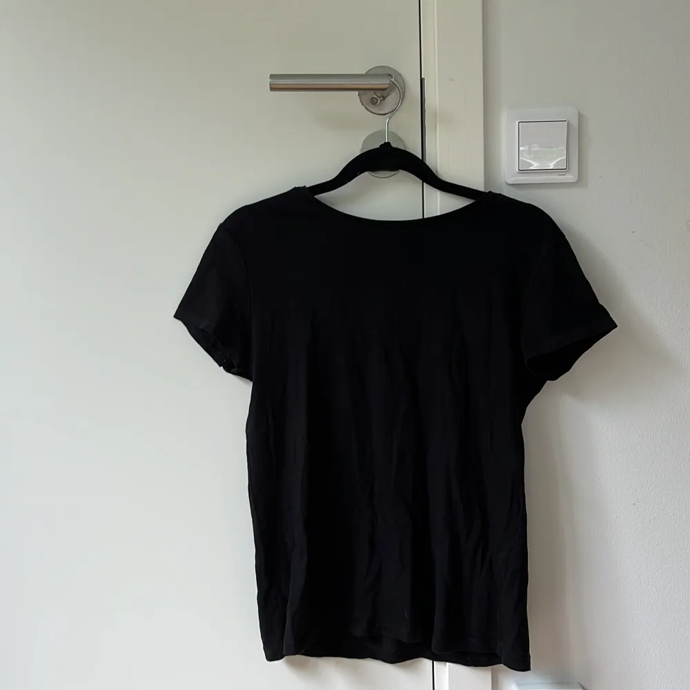 En svart t-shirt som självklart stryks innan utskick . T-shirts.