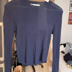 Marinblå långärmad tröja i väldigt tunt ribbat material. Lite rundad nertill. Använd några gånger men är i bra skick. 