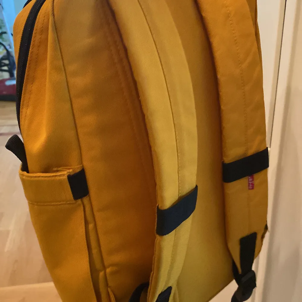 En stor Levis ryggsäck i färgen gul. Den är rymlig med ett ytterfack, ett fack på sidan samt ett fack för dator på insidan. Lite smutsig på undersidan men det går att tvätta bort. Annars är det inga synliga skador. . Väskor.
