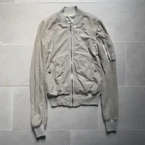 Rick Owens SS19 mainline läderbomberjacka.  Jackan är använd men i bra skick 9/10. Inga hål eller liknande.  Storlek IT 48 vilket motsvarar M, passar mer som en S/XS. Färgen är grå/vit. Vid intresse finns fler bilder och djupare beskrivning av plagget.