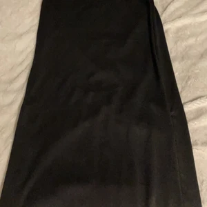 Lång svart kjol - Lång svart kjol med en zip på varje sida så man kan välja om man vill ha slit på båda sidorna eller en eller ingen. Prislappen är kvar och den är köpt från Obeject för 400kr