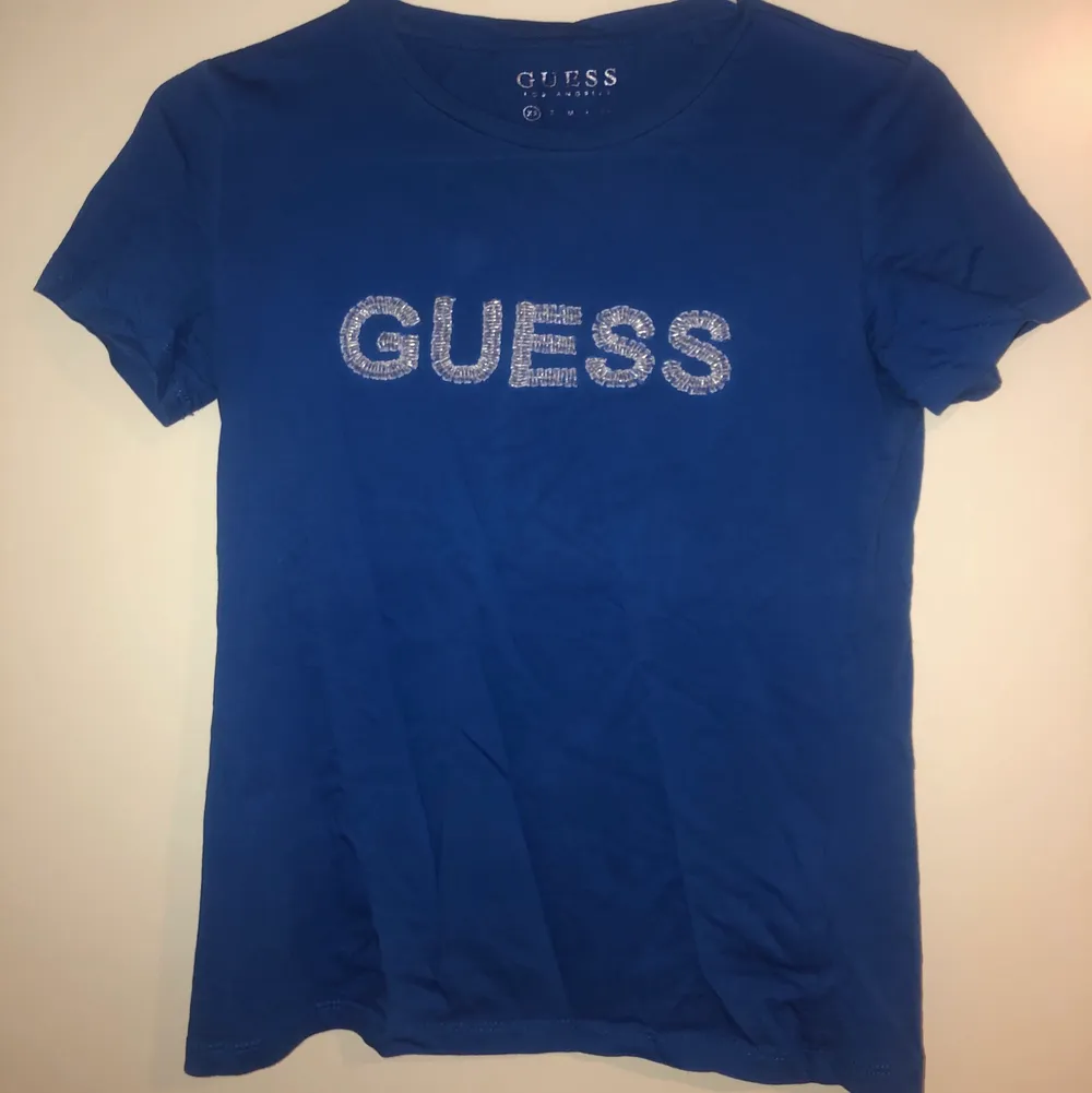 Blå T-shirt från Guess med silvrig text, storlek xs! Köpare står för frakt:). T-shirts.