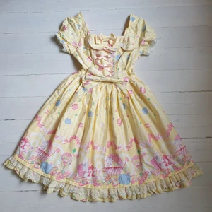 Lolita Klänning Rosa Gul - Gullig lolita klänning i bomull. Jättebra kvalitet och har många fina detaljer som rosetter, spets och snören. Stretchigt material runt midjan samt en korsettliknande snörning som går att knyta så tajt en vill. Den stora rosetten går även att ta av.