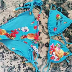 Oanvänd turkos bikini från märket Waikiki beach med snörning, stenar och guld annanser på banden. 