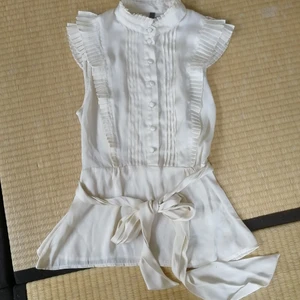 Topp glansig gräddvit H&M premium knapp - Vacker skir och glansig topp från H&M premium. Har ett bälte med hällor och knappar på framsidan, samt litet volanger/plisseringar Otroligt vacker, bara inte riktigt min stil. Man ser definitivt elegant ut i den! Fest, student, eller som uppklätt. 