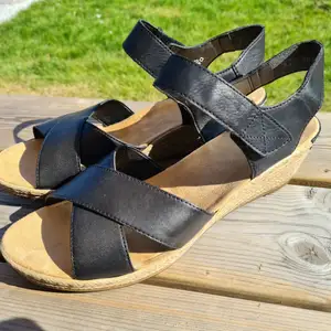 Ett par svarta sandaler med klack från Rieker. Använda ett fåtal gånger och är i fint skick. Nypris 600 :- Köparen betalar frakten!