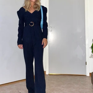 Elegant jumpsuit - Lång jumpsuit med puffärm, marinblå med vita ränder och ett skärp i midjan. Sparsamt använd. Ny pris: 1000kr