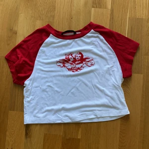 Röd/vit topp från Shein strl s - Vit kort topp med röda ärmar och rött tryck. Köpte från Shein för inte alls så länge sen och den är bara testad. Den är liiite genomskinlig men det märks knappt. 