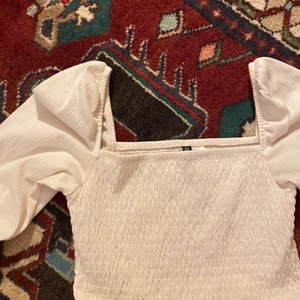 Gullig puffärm-topp - Topp med lång puffärm, köpt på HM för ett tag sen! Använd några få gånger så i bra skick. Färgen är typ vit/gräddvit. Skriv för fler bilder, frågor osv! 💕