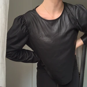 Svart skinntröja - Svart tröja med puffärmar i fake skinn. Fin till både fest och vardag. Använd flertal gånger men i fint skick. Köparen står för frakten 