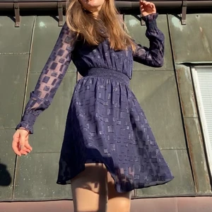 Festklänning med struktur - Festklänning i mörkblå färg från HM. Tvådelad med en enfärgad underklänning och en överklänning i ett något genomskinligt material med glittriga strukturer i tyget som ger en väldigt lyxig look på klänningen. Markering i midjan med resår vilket ger en fin form på kroppen. Använd kanske en eller två gånger. Storlek 34 men jag skulle säga att den passar en 36 också då den är stretchig. Mitt pris 200kr. 