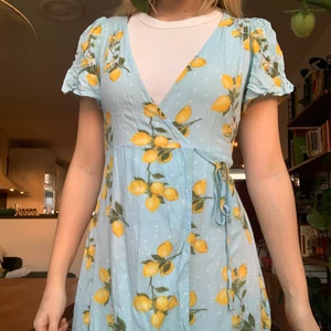 Mönstrad omlottklänning - En mönstrad omlottklänning från Forever 21 i blått med citronmönster. Frakt ingår! Storlek S.
