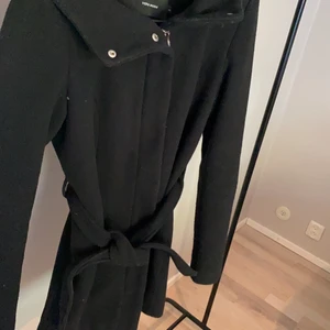 Kappa från Vero Moda - Superfin kappa från Vero Moda som nu kan bli din!✨ Kappan är endast använd en gång så är i superfint skick! Kappan har både luva och knappar samt ett midjeband. En kappa som värmer väldigt bra i kylan! Jag köpte kappan för 599kr men jag säljer den nu för 200kr. Perfekta kappan nu inför hösten och vintern!❄️ Passa på!✨