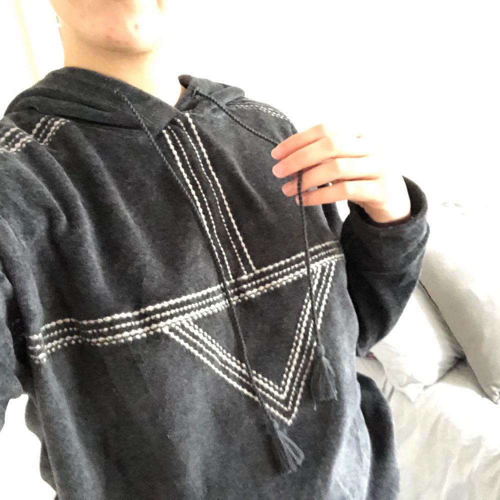 Gray thin sweater with ethnic patter and hood. Soft fabric similar to velvet. It has two strings hanging from the hood with a pompom at the end. It is loose or baggy.. Huvtröjor & Träningströjor.