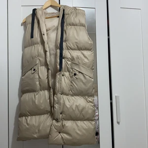 Lång väst - Väldigt fin beige väst, ganska lång kommer ungefär ner till knän. Helt ny och oanvänd. Säljer den för tycker inte den passade mig så jätte bra.