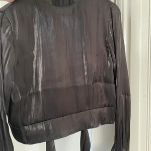 Blus - Super fin blus helt oanvänd med fin knytning bak. Stl: 42. Helt oanvänd. Färg: svart. Från NAKD