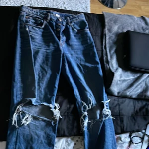 Jeans med design - Säljer dessa vida jeans från Hm i storlek 38. Har tönt ut hålen lite mer. Har även målat lite själv på fickorna med vattenfast penna från panduro som är till för textilkläder är precis lite för korta för mig och jag är 170 lång