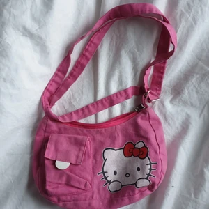 hello kitty väska  - Säljer denna super gulliga hello kitty väskan!! Det är en liten tråd som sticker ut på ena sidan, men det är inget man tänker på när man använder den. Kontakta om frågor/ mer bilder.