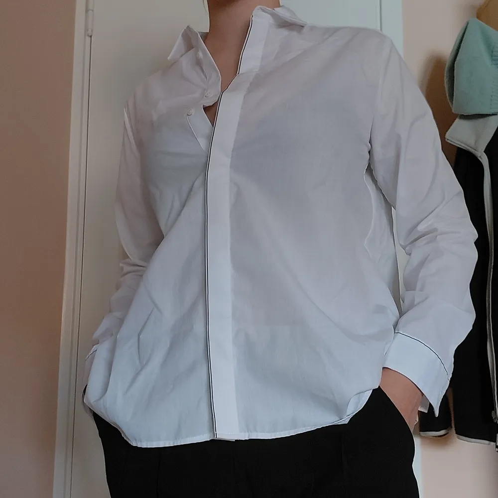 En festlig skjorta från Zara, med snygga svarta detaljer vid krage, knappar och ärm. Modellen är lite rakare och vidare nedtill. Säljer den då den är lite för liten för mig nu. Bara använd en gång! Köparen står för frakten men kan även mötas upp i gbg💛. Skjortor.