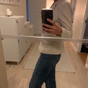 Beige kavaj från H&M - En beige kavaj från H&M. Då lappen för stoleken var bortklippt uppskattar jag stoleken till S. Den säljs då jag inte själv känner mig bekväm att bära kavaj. Fint skick och ett snyggt snitt på nedre delen av ryggen.