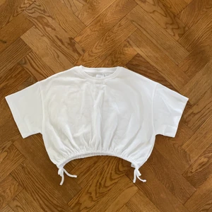 Tröja - Vit kroppad t-shirt med rosetter och resår nertill! Från zara i storlek 152, är som en xxs/xs. Använd två gånger så i väldigt fint skick! 