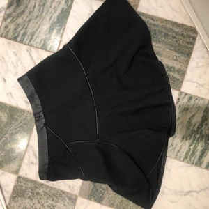 Trendig kjol - Svart med läderdetaljer och volang