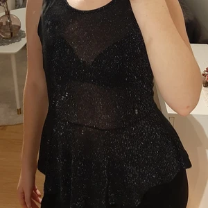 Svart och glittrig topp från Veromoda - En lite festligare topp som passar perfekt till nyår. Toppen är i storlek S. Knappt använd. Toppen är svart och tunn även lite genomskinlig med glitter. Längst ned är den klockad/volang. Köparen står för eventuell frakt.