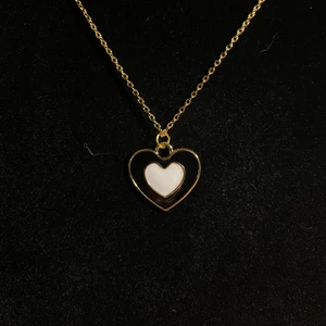 Halsband med svart/vitt hjärta - Halsband i rostfritt stål. Guldpläterad samt emaljerad berlock. Fri frakt✨