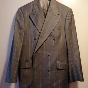 Exklusiv Tiger of Sweden Ull Kostym - Denna ull kostym är av högsta kvalitén och tillhör Tigers fina Collection. Modellen heter Cassius och är otroligt fin sydd. Design på denna inte bara andas exklusivitet men också känns så när man har på sig den. Det är grå färg med ljusgrå ränder med dubbel bröstad knäppning och sex knappar. Det är en peaked lapel med flap fickor och dubbla vents. Det 100% ren ull. Använd endast ett fåtal gånger så både kavaj och byxor är i absolut nyskick.  Kostar ny i butik: 6750:- / Säljes för endast: 550:-