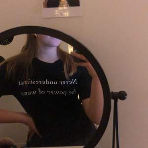 Svart t-shirt med texten ’Never underestimate the power of women’ Är i storlek S men passar även mig med M beroende på hur man vill att den ska sitta! 