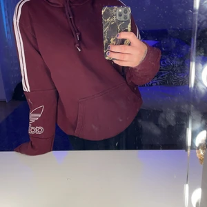 Adidas hoodie  - En vinröd adidas hoodie. Säljer på grund av att den inte kommer till användning men den är jätte fin och varm. Adidas ränder till armbågarna och ett adidas märke på vänster arm. Skriv för mer bilder och andra frågor. <3