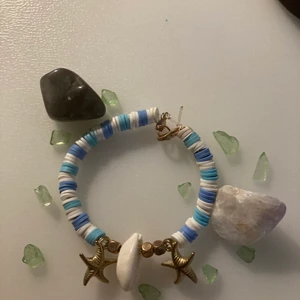 armband  - Armband med vita och ljusblå clay beades,snäckskal och sjöstränorpch elastisk tråd. Runt 20 cm. 