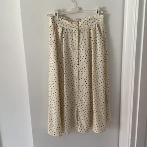 Prickig kjol - Benvit midi kjol med svarta prickar på och knappar hela vägen. Från märket Monki. Väldigt fint skick!