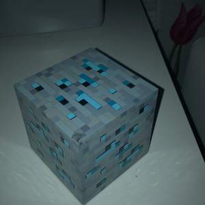 Detta är en Minecraft baserad nattlampa. Den lyser i blått (batterierna i den var döda dock, så kan inte visa). Påtal om det, så ingår inte batterier. För att sätta på den, knackar man lätt på den. Destu mer man knackar, destu mer lyser den :)