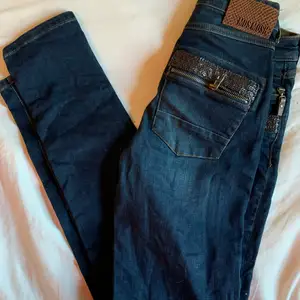 Märkesjeans Mos Mosh jeans Naomi med äkta läderdetaljer och dragkedjor vid fickorna. Stuprörsmodell/slim fit storlek 25. Bra strech därav väldigt bekväma. Unika i sin stil. Nypris 1300kr